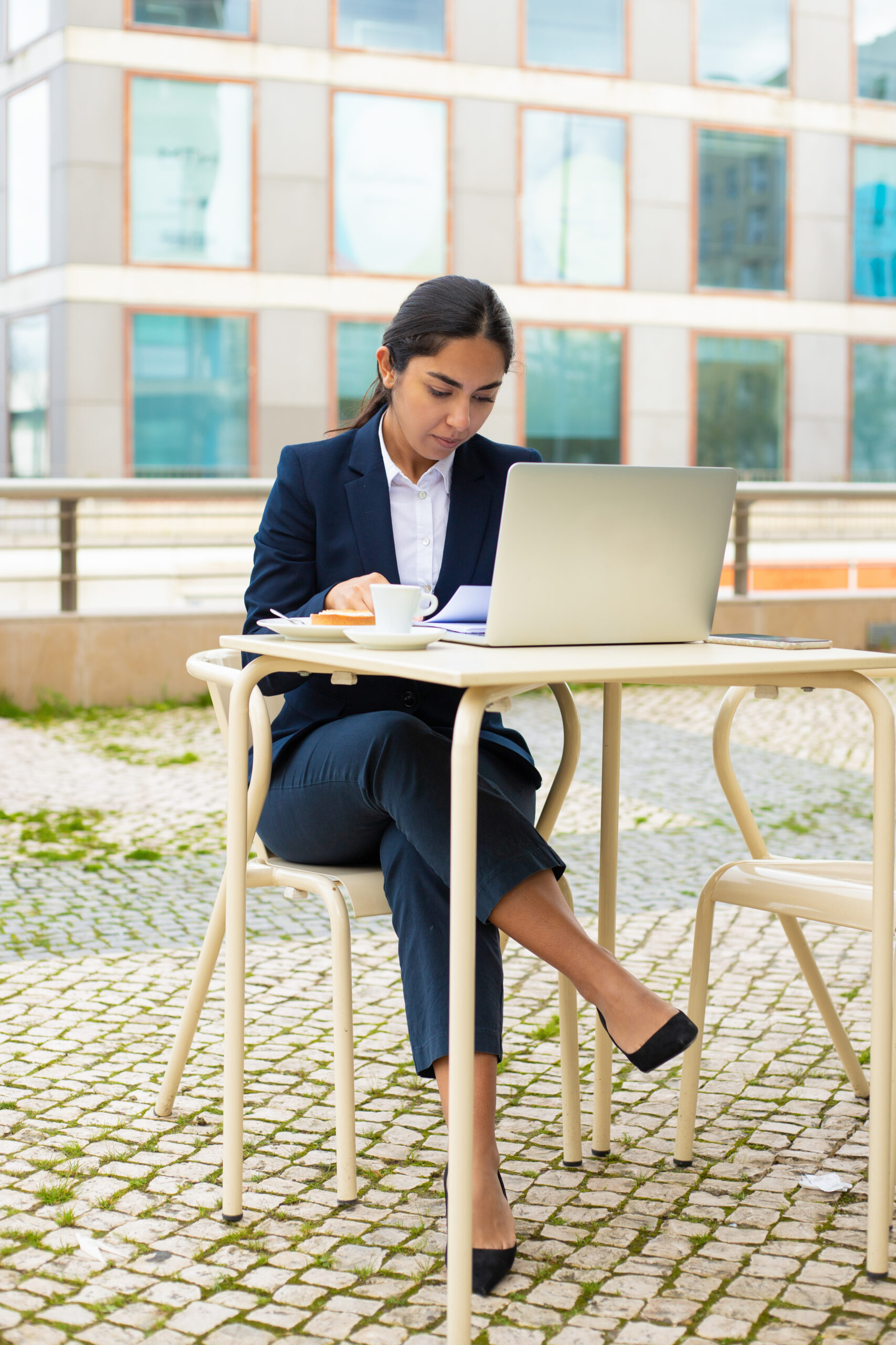 Businesswoman with laptop and papers in cafe Businesswoman with laptop and papers in cafe. Foused young businesswoman working with papers and laptop computer while sitting in outdoor cafe. Business concept